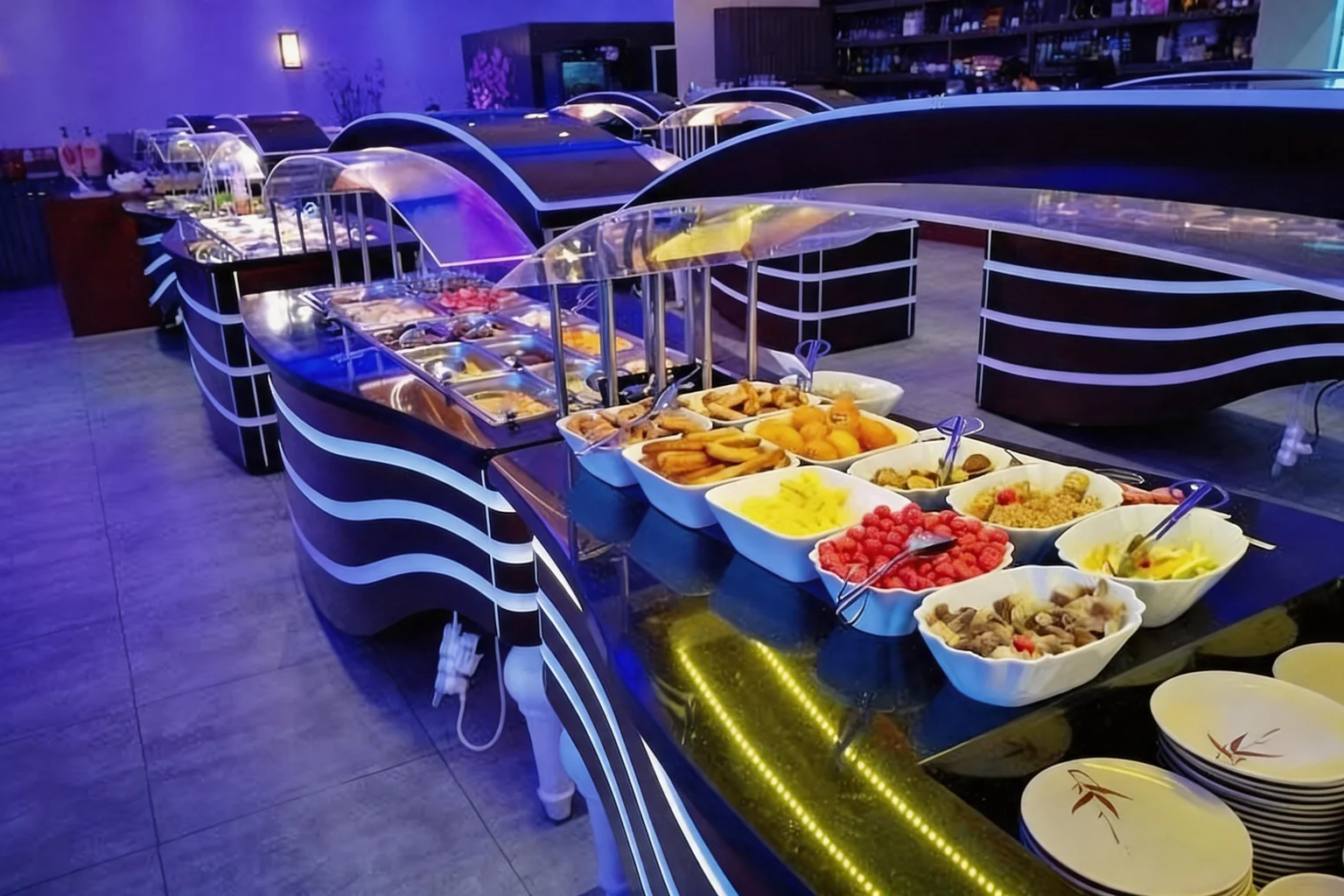 Blue-lit buffet counters, filled white bowls and stacks of plates.