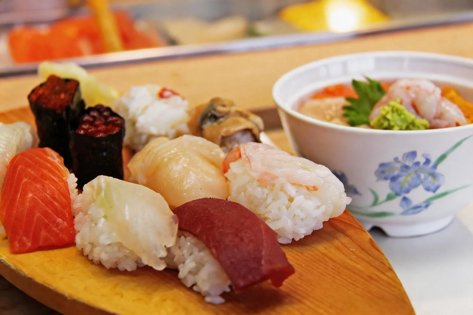 Sushi on a wooden board, white bowl with an iris pattern.